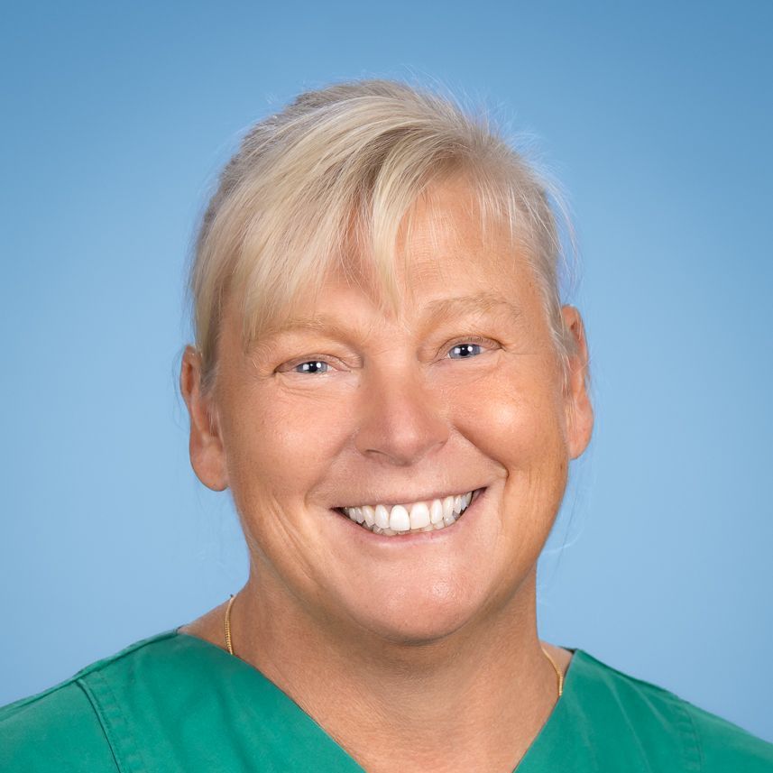 Eine Frau im grünen OP-Kittel lächelt in die Kamera.