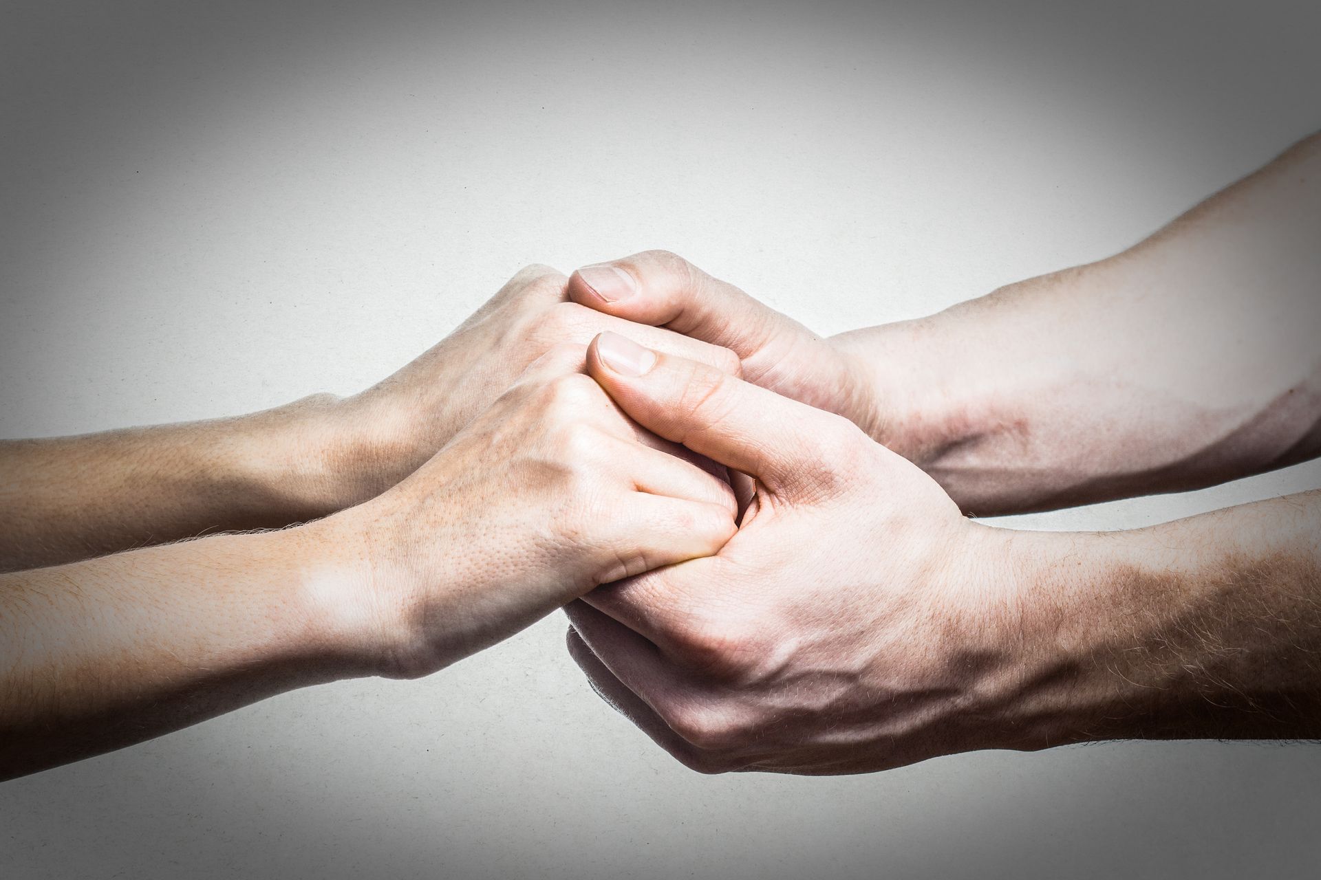 Ein Mann und eine Frau halten vor einem grauen Hintergrund Händchen.