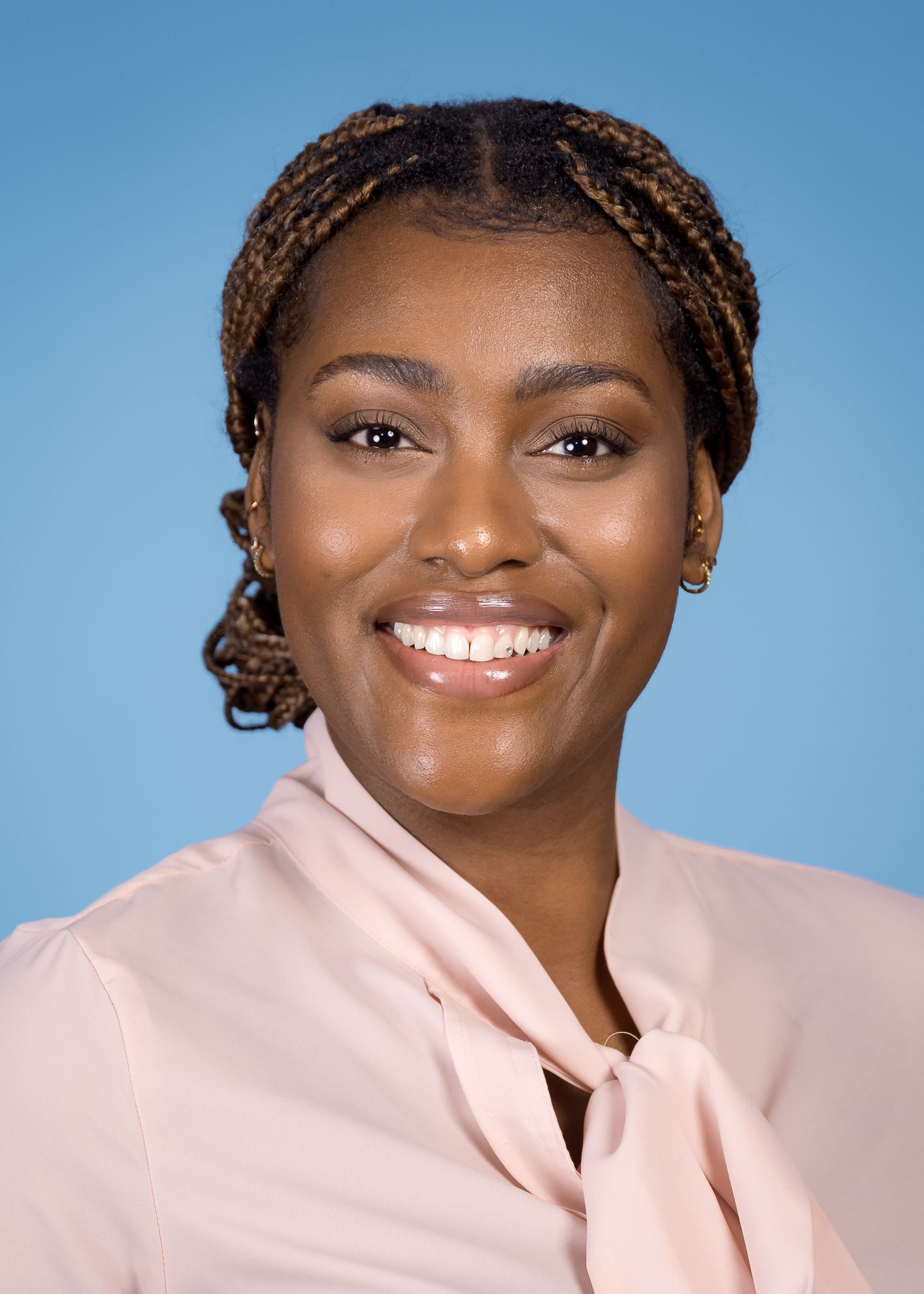 Eine Frau mit langen blonden Haaren trägt einen rosa Pullover und ein weißes Hemd.