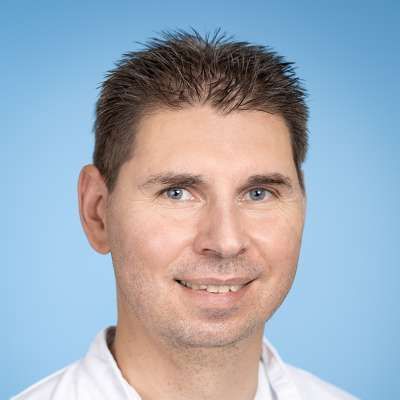 Ein Mann in einem weißen Hemd lächelt in die Kamera.