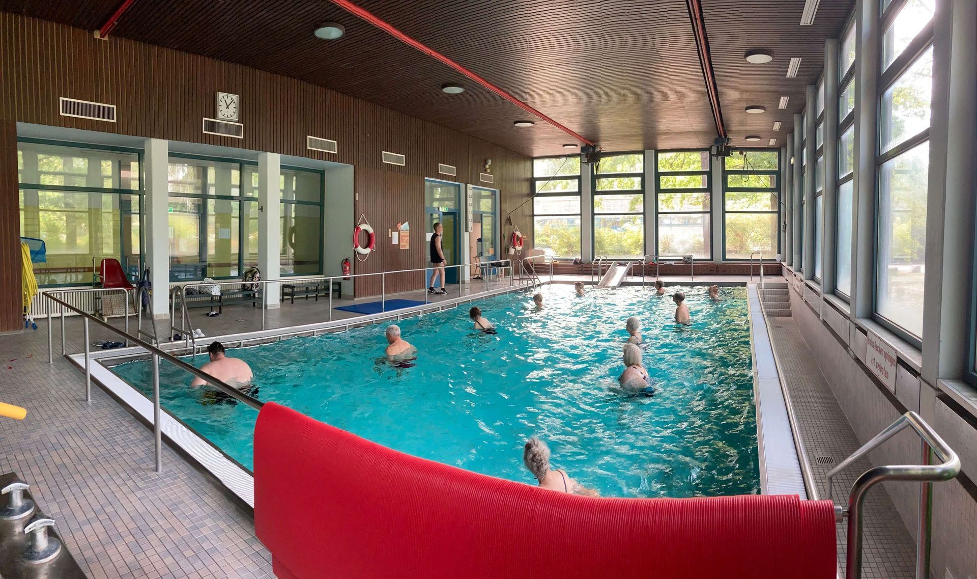 Eine Gruppe von Menschen schwimmt in einem großen Hallenbad.