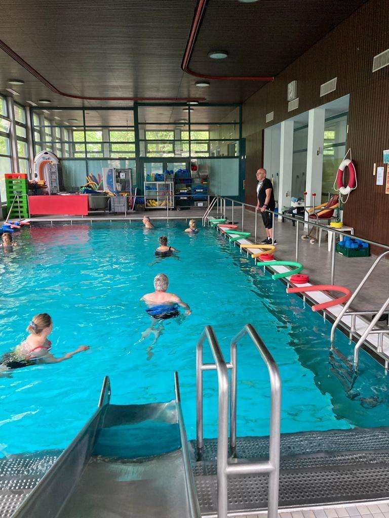 Eine Gruppe von Menschen schwimmt in einem großen Hallenbad.