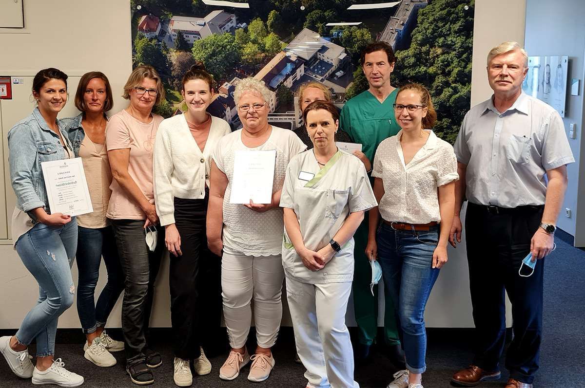 Eine Gruppe von Menschen posiert für ein Foto vor dem Bild eines Krankenhauses.