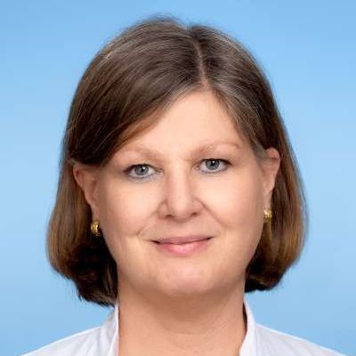 Eine Frau in einem weißen Hemd und mit Ohrringen lächelt in die Kamera.