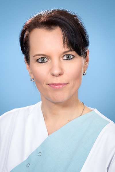 Eine Frau in einer weiß - blauen Uniform lächelt in die Kamera.