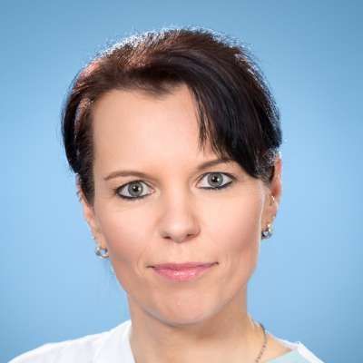 Eine Nahaufnahme des Gesichts einer Frau vor blauem Hintergrund.