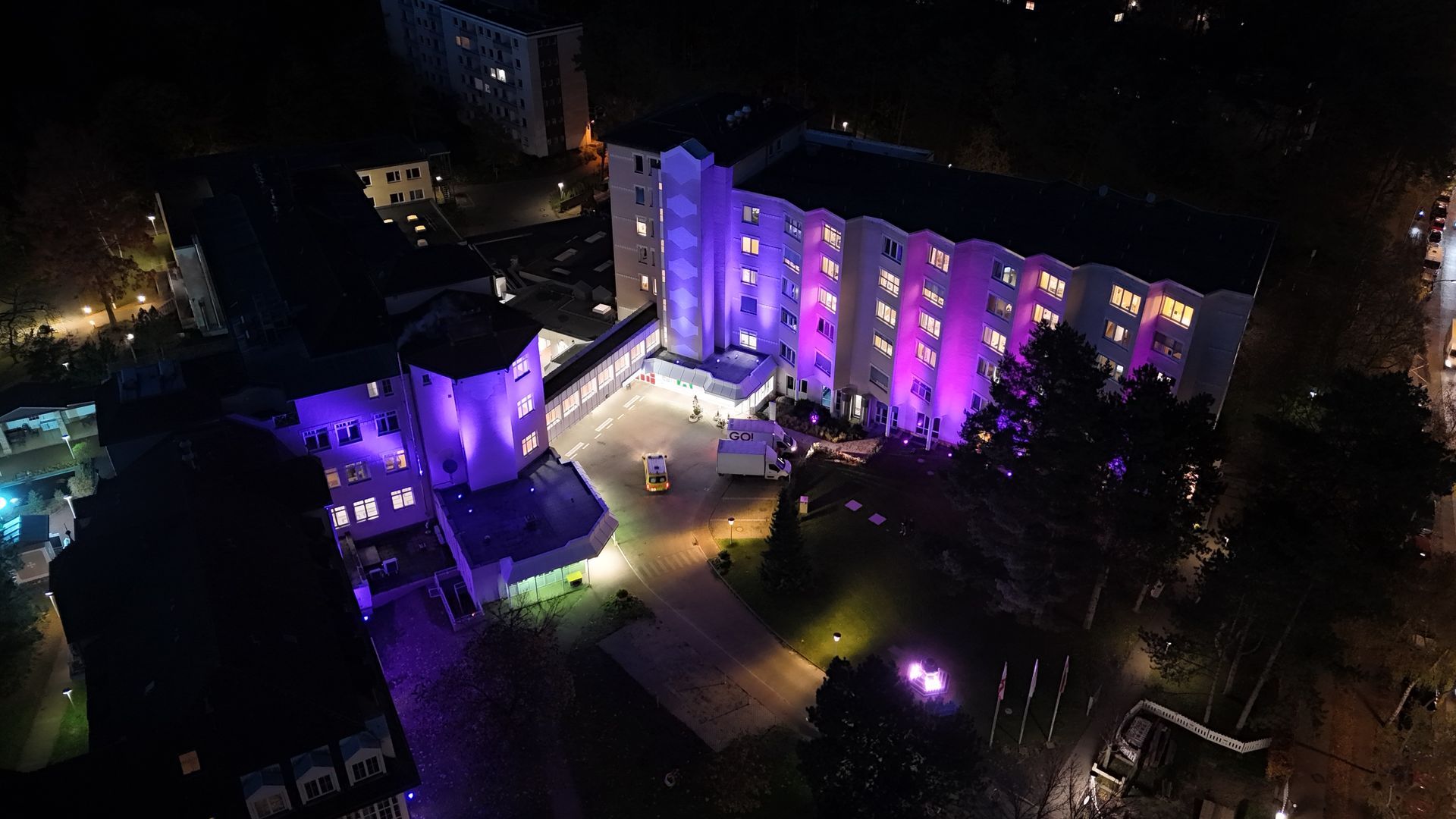 Eine Luftaufnahme eines Gebäudes, das nachts mit violetten Lichtern beleuchtet ist.