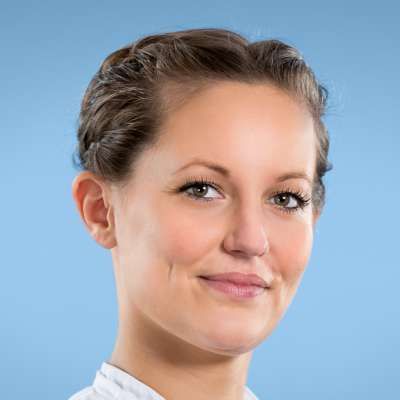 Eine Nahaufnahme des Gesichts einer Frau vor blauem Hintergrund.