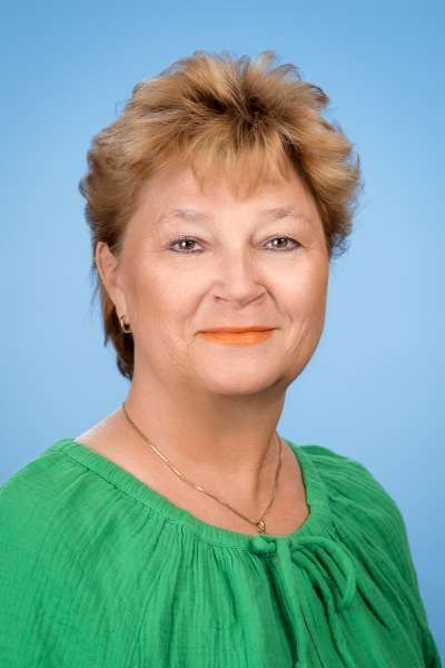 Eine Frau in einem grünen Hemd lächelt in die Kamera.