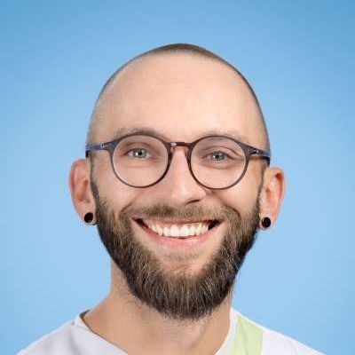 Ein Mann mit Bart und Brille lächelt in die Kamera.