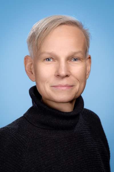 Ein Mann in einem schwarzen Rollkragenpullover lächelt in die Kamera.