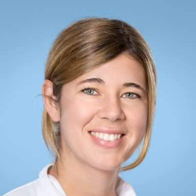 Eine Frau lächelt in die Kamera und trägt ein weißes Hemd.