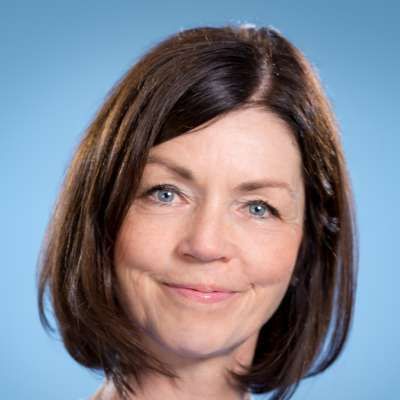 Eine Nahaufnahme des Gesichts einer Frau vor blauem Hintergrund.