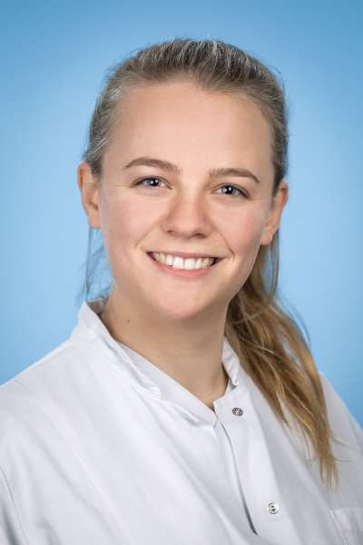 Eine Frau in einem weißen Laborkittel lächelt in die Kamera.