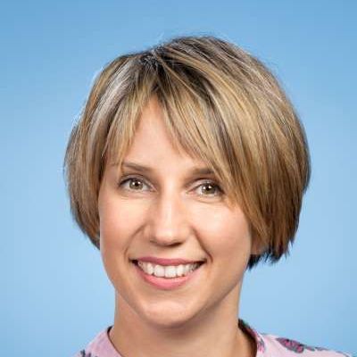 Eine Frau mit kurzen blonden Haaren lächelt in die Kamera.