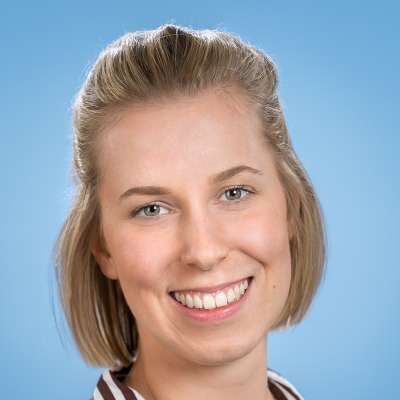 Eine Nahaufnahme des lächelnden Frauengesichts vor blauem Hintergrund.