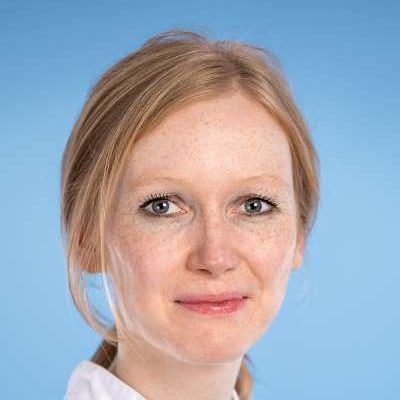 Eine Nahaufnahme des Gesichts einer Frau vor blauem Hintergrund.