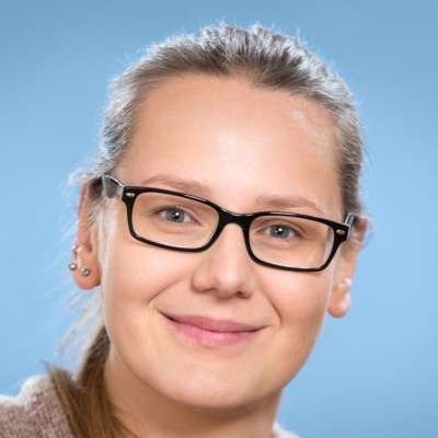 Eine Nahaufnahme einer lächelnden Frau mit Brille.