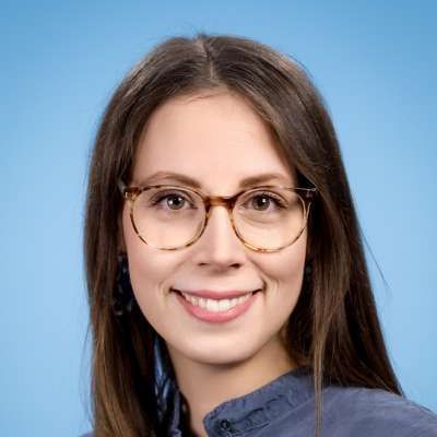 Die Frau trägt eine Brille und lächelt in die Kamera.