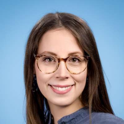 Die Frau trägt eine Brille und lächelt in die Kamera.