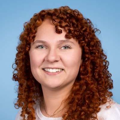 Eine Frau mit roten Locken lächelt in die Kamera.