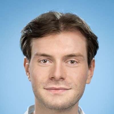 Eine Nahaufnahme des Gesichts eines Mannes vor blauem Hintergrund.