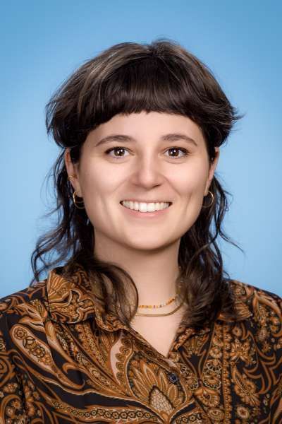 Eine Frau in einem Paisley-Hemd lächelt in die Kamera.