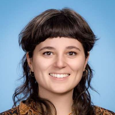 Eine Nahaufnahme des Gesichts einer Frau vor blauem Hintergrund.