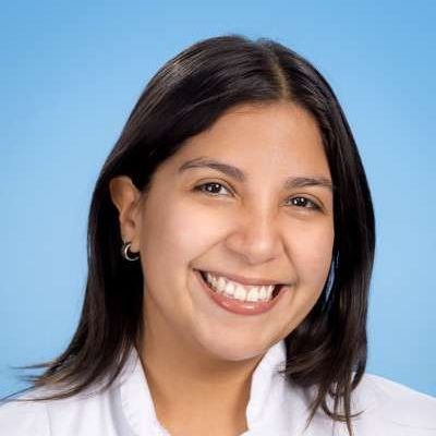 Eine Frau in einem weißen Laborkittel lächelt in die Kamera.