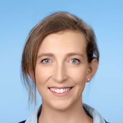 Eine Nahaufnahme des lächelnden Frauengesichts vor blauem Hintergrund.