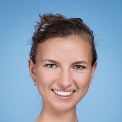 Eine Nahaufnahme des lächelnden Frauengesichts vor blauem Hintergrund.