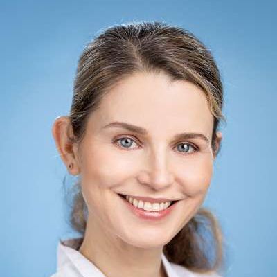 Eine Nahaufnahme des lächelnden Frauengesichts vor blauem Hintergrund.