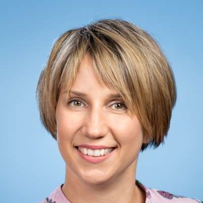 Eine Frau mit kurzen blonden Haaren lächelt in die Kamera.