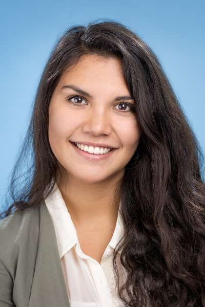 Eine Frau mit langem dunklem Haar lächelt in die Kamera.