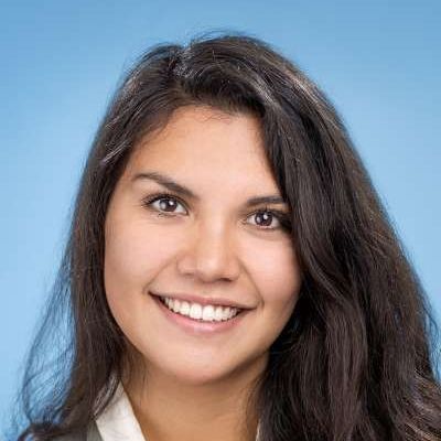 Eine Frau mit langem dunklem Haar lächelt in die Kamera.