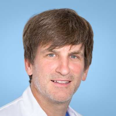 Ein Mann im weißen Laborkittel lächelt in die Kamera.