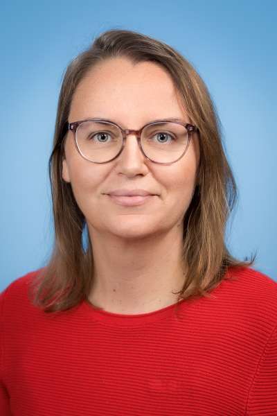 Eine Frau mit Brille und rotem Hemd posiert für ein Foto.