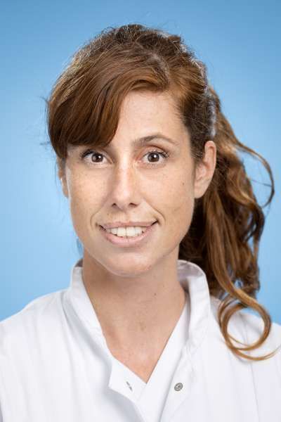 Eine Frau in einem weißen Laborkittel lächelt in die Kamera.