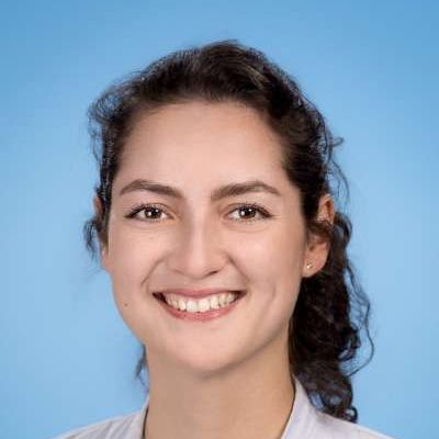 Eine Nahaufnahme des lächelnden Frauengesichts vor blauem Hintergrund.