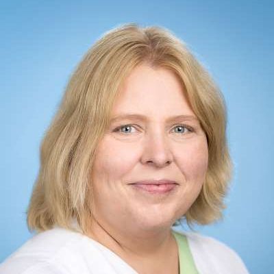 Eine Nahaufnahme des Gesichts einer Frau vor blauem Hintergrund.