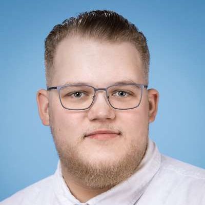 Ein Mann mit Bart und Brille trägt ein weißes Hemd und eine Krawatte.