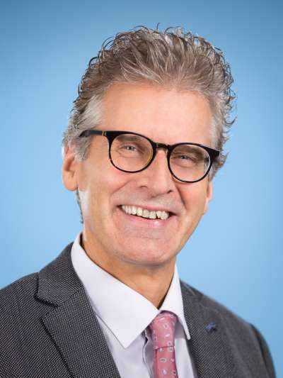 Ein Mann in Anzug und Krawatte lächelt in die Kamera.