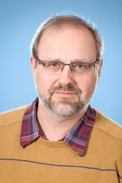 Ein Mann mit Bart, Brille und kariertem Hemd