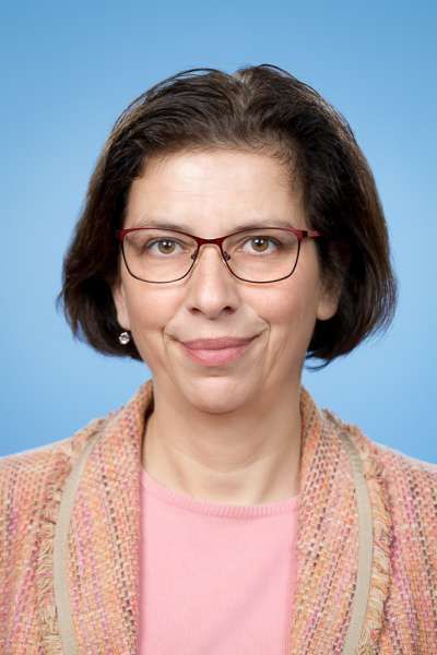 Eine Frau mit Brille und rosa Hemd lächelt in die Kamera.