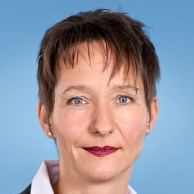 Eine Nahaufnahme des Gesichts einer Frau vor blauem Hintergrund.