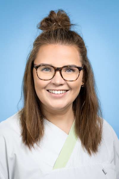 Eine Frau mit Brille und weißem Kittel lächelt in die Kamera.