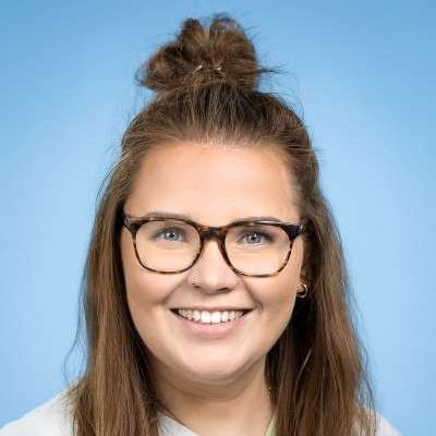 Eine Frau mit Brille und Dutt lächelt in die Kamera.