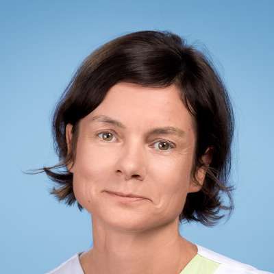 Eine Nahaufnahme des Gesichts einer Frau vor blauem Hintergrund.