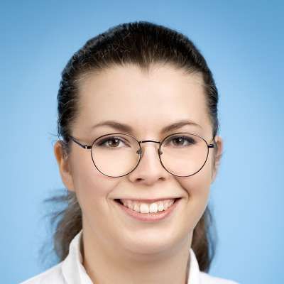 Eine Frau mit Brille und weißem Hemd lächelt in die Kamera.