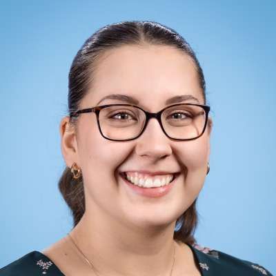 Eine Frau mit Brille und Ohrringen lächelt in die Kamera.